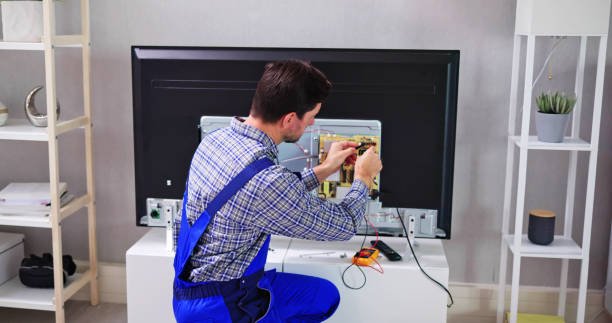 Young Male Electrician In Overall Checking Television